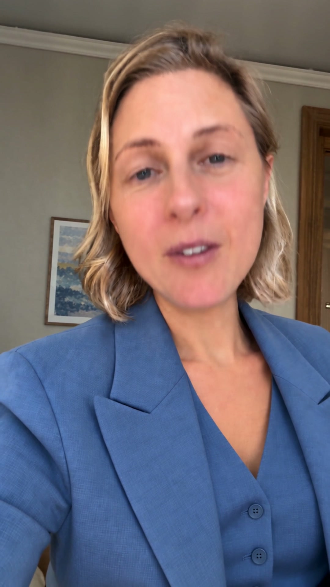 Before upscaling: the complete portrait frame, showing the presenter in a blue blazer and the room behind her.